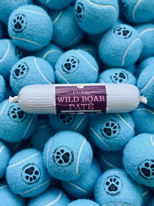 Blue tennis balls with paw prints and a roll of 'Pure Wild Boar Paste' on top.