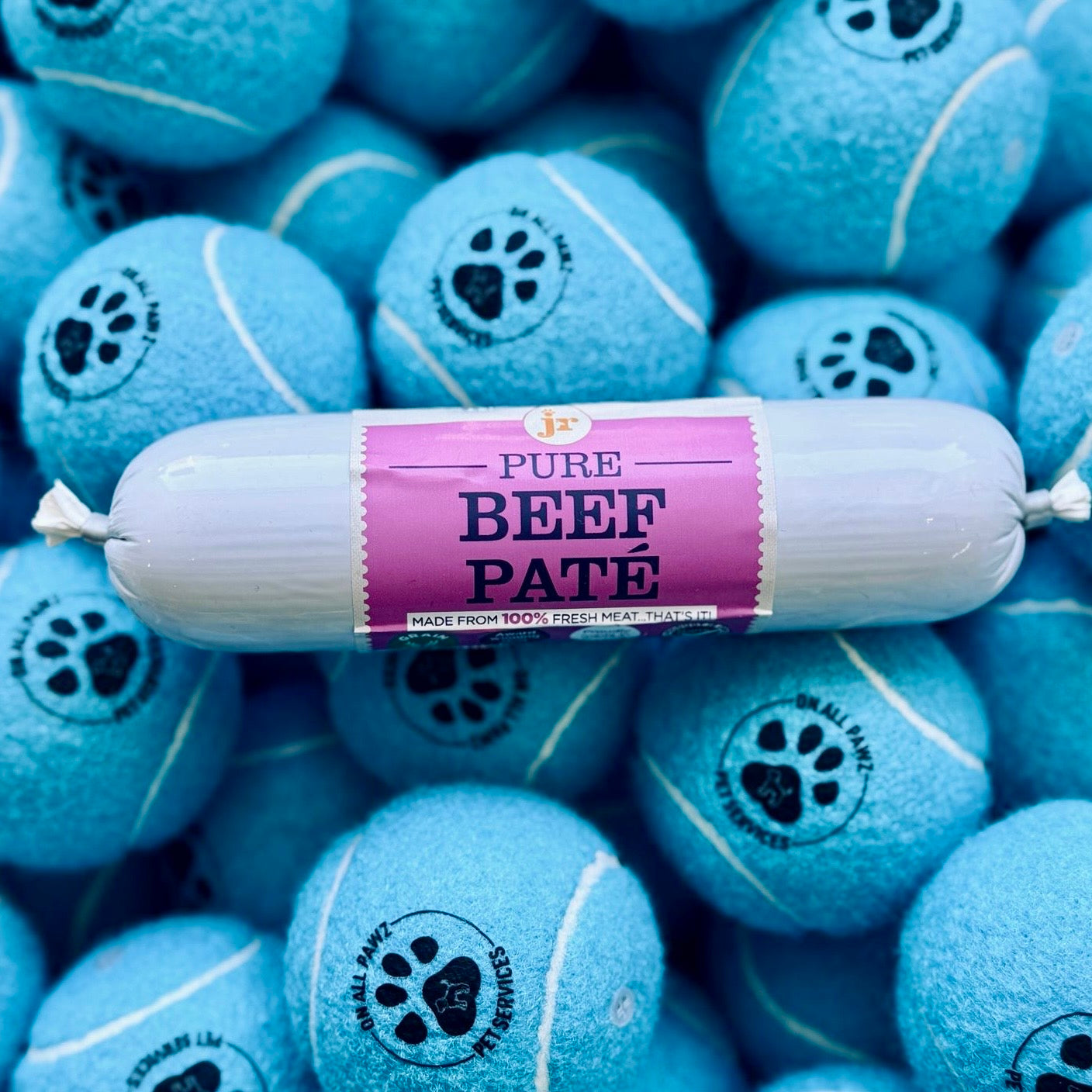 Blue tennis balls with paw prints and a package of beef pâté on top.