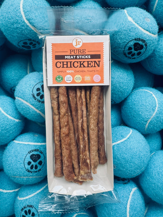 Package of chicken meat sticks surrounded by blue tennis balls with paw prints on a clear background