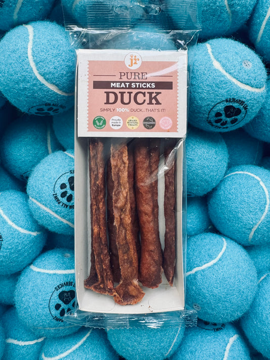 Pack of duck meat sticks with packaging on a background of blue tennis balls.
