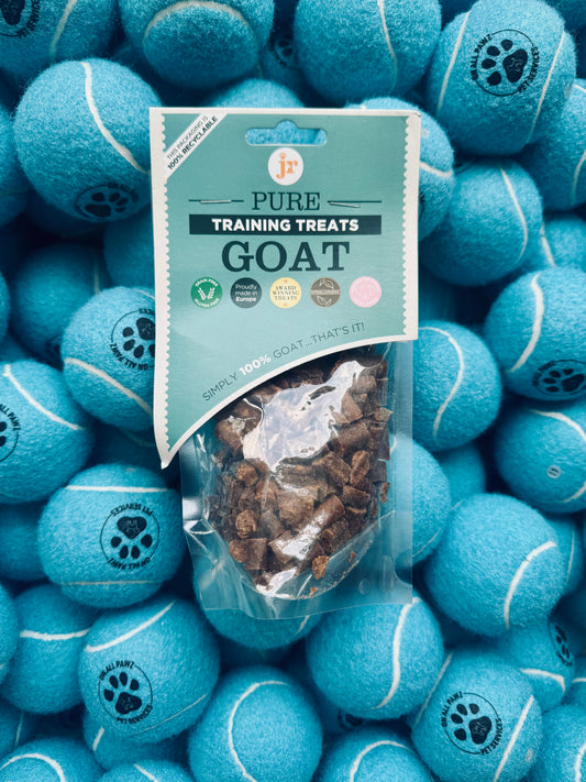 Bag of goat training treats surrounded by blue tennis balls with paw prints on a pile.