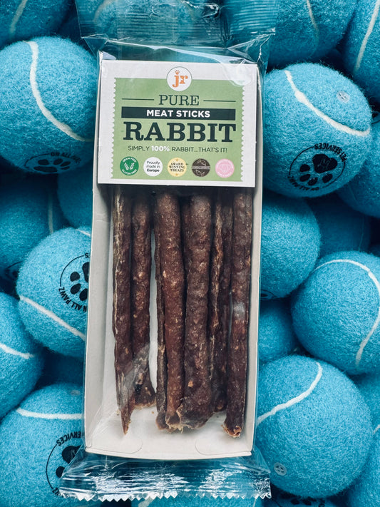 Pack of Pure Meat Sticks Rabbit treats with blue tennis balls in the background