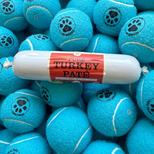 Turquoise tennis balls with paw prints and a package of Pure Turkey Pate on top.