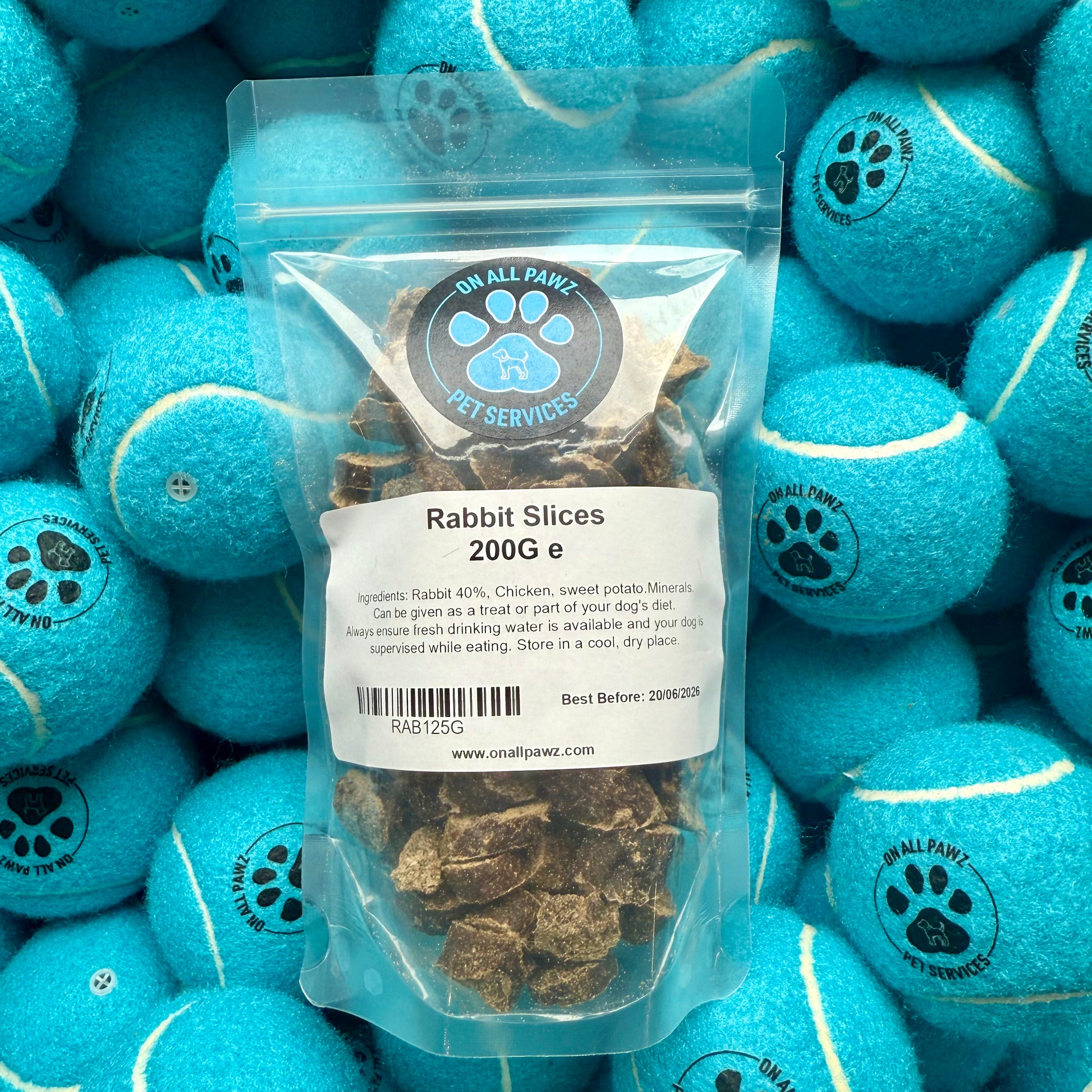Bag of rabbit slices with blue tennis balls branded 'On All Paws' in the background
