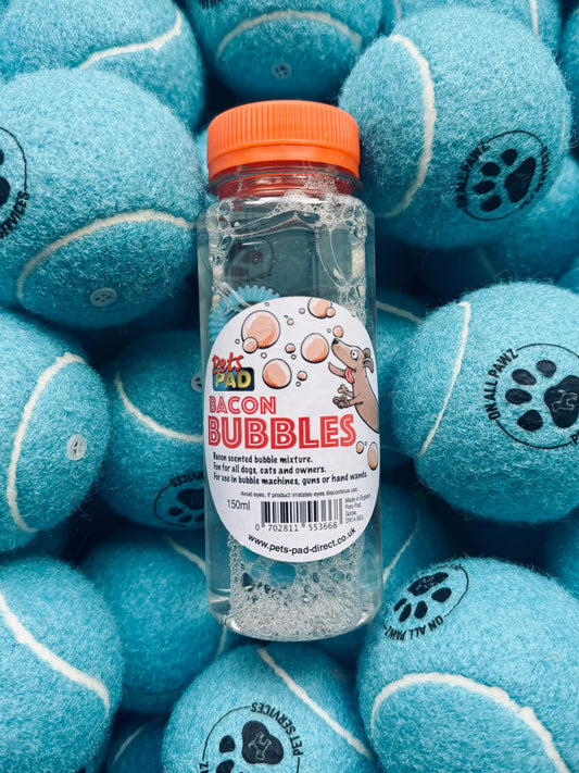 Bottle of Bacon Bubbles product surrounded by blue tennis balls with paw prints.