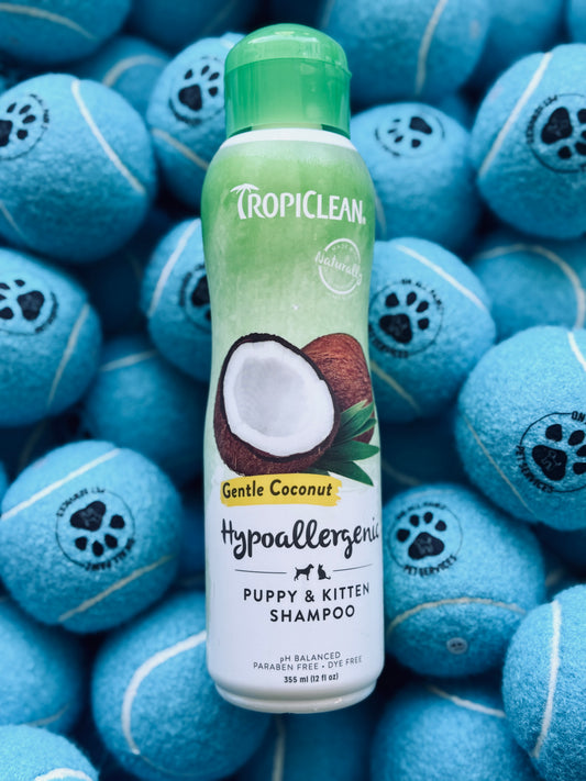 A bottle of Tropiclean Gentle Coconut Shampoo for pets, with a background of blue tennis balls.