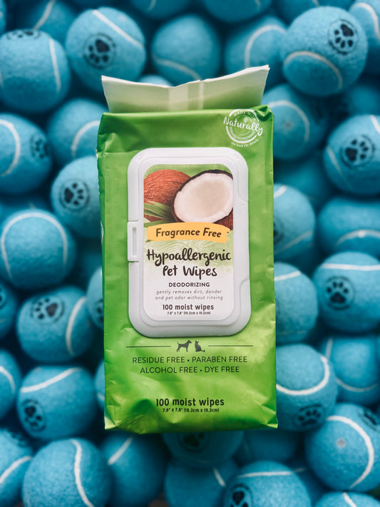 A pack of TropiClean Hypoallergenic Pet Wipes placed on a background featuring multiple blue pet toys shaped like tennis balls.