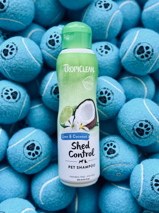 A bottle of Tropiclean Lime and Coconut Shampoo for pets, placed on a background with blue tennis balls.