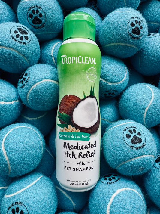 TropiClean shampoo bottle surrounded by blue tennis balls with paw prints on a blue background