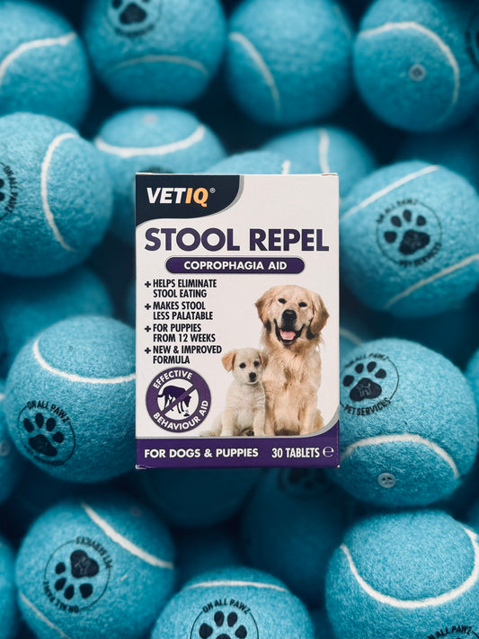 A box of VETIQ Stool Repel Tablets for dogs and puppies, placed on a background of blue dog treats.